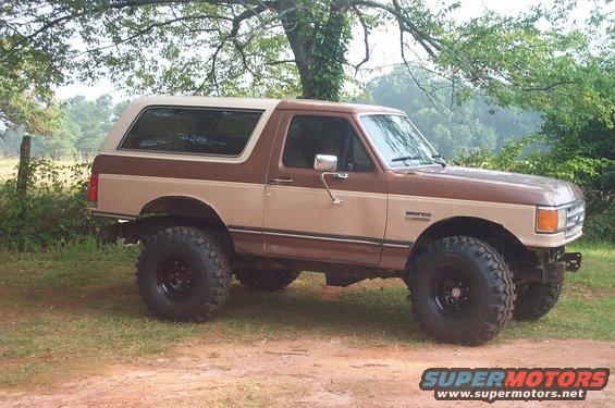 Brown 1987 Ford Bronco with body lift and large tires parked outdoors