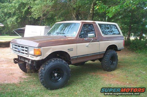 1987 Ford Bronco with body lift and large tires parked on grass