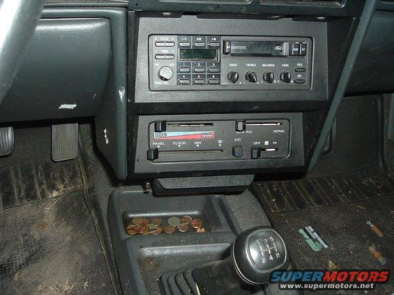Interior view of a car's center console with a manual shifter, radio, and climate controls