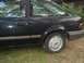 1989 Ford Escort - This dark sedan, possibly from the late 1980s, is parked on a grassy area next to a building.