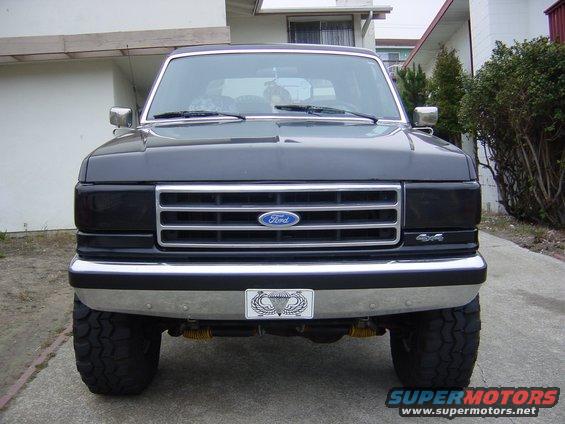 1990 Ford Bronco, dark gray, front view, chrome grille, aftermarket bumper with parachute patch, large tires