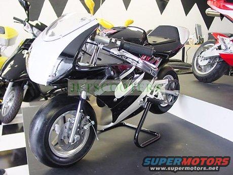 Black and white mini motorcycle on a stand. Another scooter and part of a red motorcycle are visible