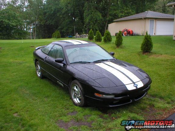 Black 1997 Ford Probe with white racing stripes parked on a grassy lawn