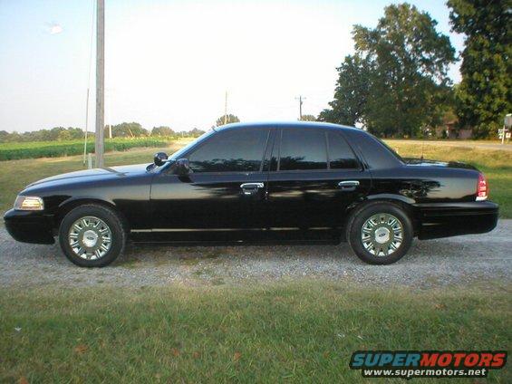 Black sedan with tinted windows parked on a gravel road