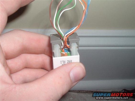 Hand holding a telephone wiring connector with multiple colored wires connected