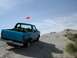 1994 Ford Bronco - A blue convertible SUV is parked on a sand dune under a clear blue sky with some clouds.