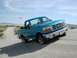 1994 Ford Bronco - A blue pickup truck navigates a sandy terrain under a clear sky.