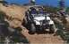 1990 Ford Bronco - A white Jeep CJ-7 navigates a challenging off-road trail with steep inclines and rocky terrain.