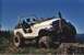 1990 Ford Bronco - White Jeep CJ-7 navigates an off-road trail with a large tire placed on a tree stump.
