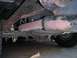 1994 Ford Bronco - The undercarriage of a vehicle displays its rear axle, leaf springs, and exhaust system, showing signs of rust and age.