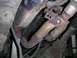 1994 Ford Bronco - Close-up of rusted exhaust system parts and driveshaft from underneath a vehicle.
