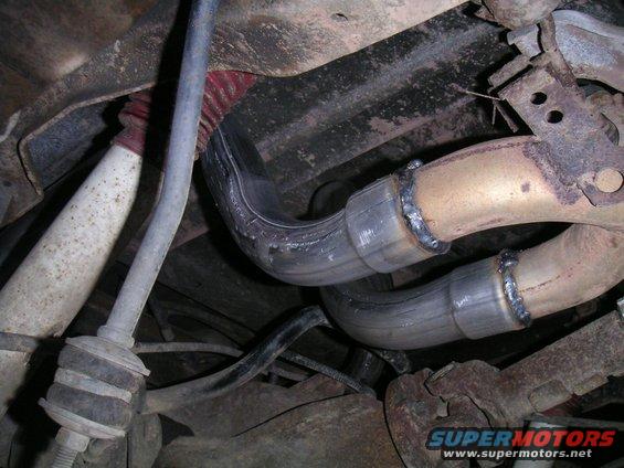 Underside view of a vehicle's exhaust system with new pipe sections welded in place
