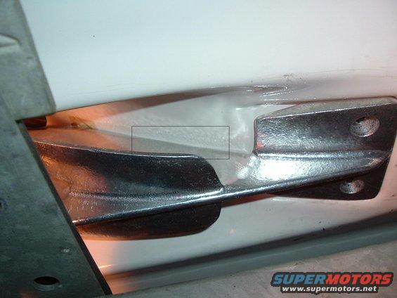 Close-up of a vehicle's door hinge mechanism, showing metal brackets and part of the white body panel
