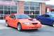 2004 Ford Mustang - Two Ford Mustangs, one orange and one blue, are parked in front of a building with large windows.