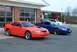 2004 Ford Mustang - Two Ford Mustangs, one orange and one blue, are parked outside a service station.