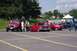 1995 Ford Mustang - A red pickup truck is parked in a lot with other vehicles and people.