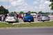 1995 Ford Mustang - Several cars are parked in a lot on a sunny day, with people milling around.