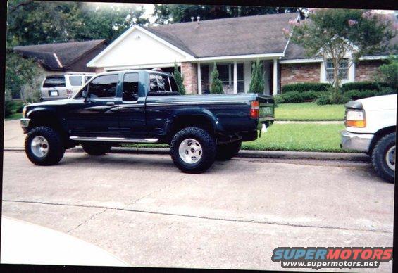 Dark blue pickup truck with lifted suspension and chrome trim parked on a street