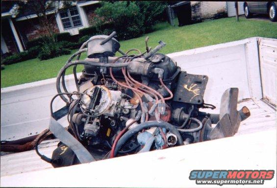 Engine assembly with carburetor and spark plug wires, resting in a white truck bed