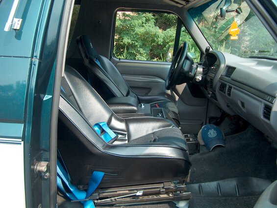 Interior of a green SUV showing black seats with blue seatbelts and dashboard