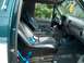 1994 Ford Bronco - The interior of a green SUV is visible, black seats with bright blue seatbelts and a gray dashboard.