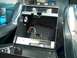 1994 Ford Bronco - Aftermarket stereo and amplifier installed in a car's center console, with black seats and blue seatbelt.