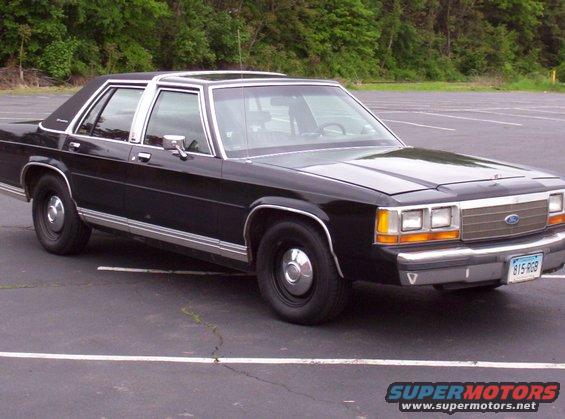 Black Ford Crown Victoria parked in a lot. License plate reads 815 RGB