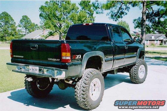 Black Chevrolet Silverado pickup truck with lifted suspension and large tires, viewed from the rear