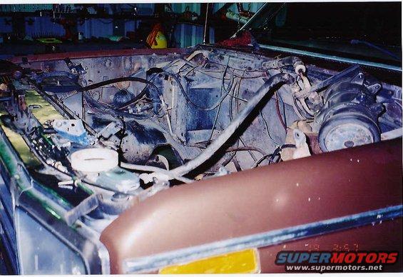 Engine bay of a vehicle with wires and parts exposed. A "SUPERMOTORS.NET" watermark is visible