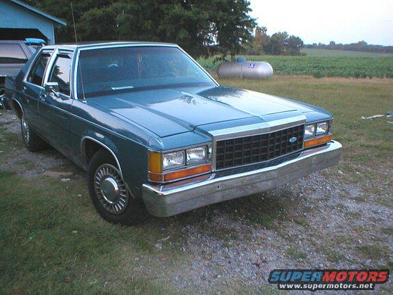 Teal 1987 Ford Crown Victoria LTD sedan parked on gravel with grass and a field in the background