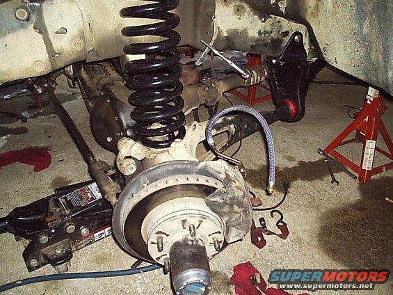 Front suspension and brake assembly on jack stands, with a hydraulic jack visible