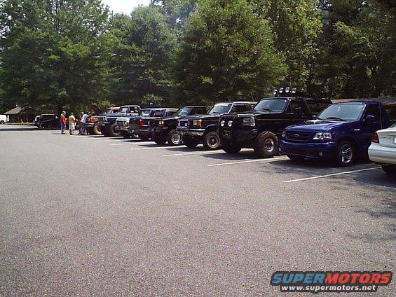 Several trucks and SUVs parked in a lot, some with lifted suspensions and off-road tires