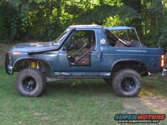 1986 Ford Bronco with snorkel, roll cage, and off-road tires parked on grass