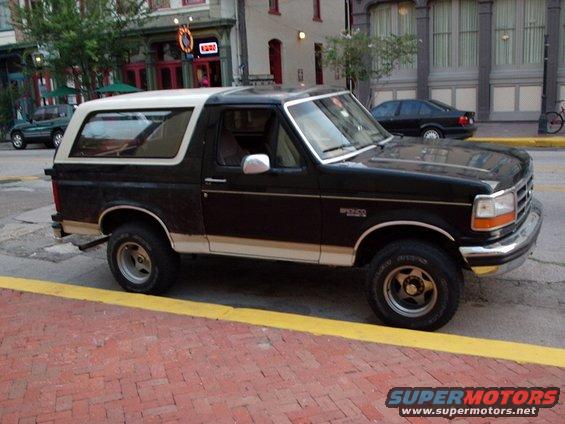 Black and white Ford Bronco parked on a brick street, side view