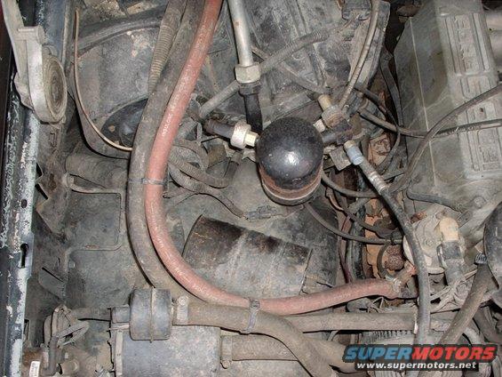 Engine bay with hoses, AC accumulator, and various engine components visible