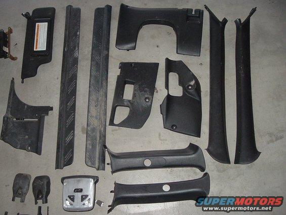 Various black plastic interior trim pieces, including door sill protectors, pillar covers, and a sun visor