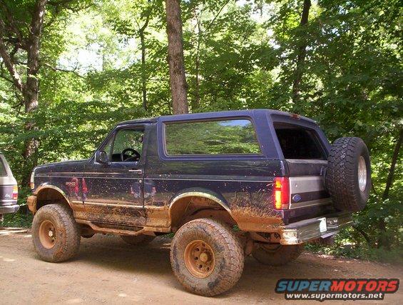 Mud-covered dark blue 1994 Ford Bronco with spare tire on rear