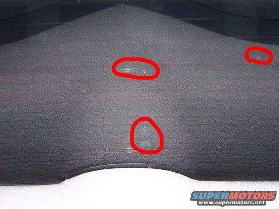 Dark gray textured dashboard with three red circles highlighting scuffs or damage