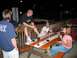 1995 Ford Bronco - A group of friends gather around a picnic table outdoors at night, enjoying drinks and conversation.