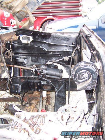 Engine bay view showing steering box and horn. Other vehicles visible in background