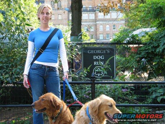 Woman with two golden retrievers in front of a sign that says "George's Dog Run"