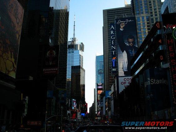Times Square with tall buildings and billboards under a clear blue sky