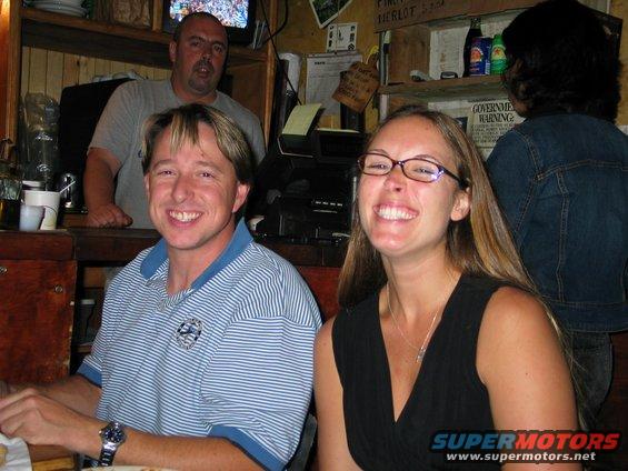 People smiling at a bar counter with a bartender in the background