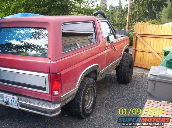 Red 1983 Ford Bronco with snorkel and large tires parked outdoors