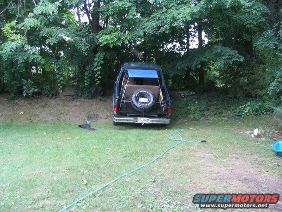 1986 Ford Bronco rear view with spare tire and blue tarp covering the open top