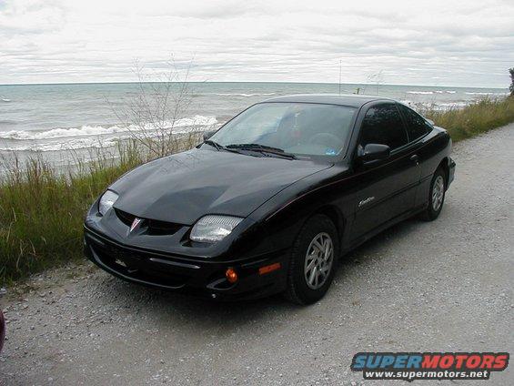 Black Pontiac Sunfire coupe parked by a lake