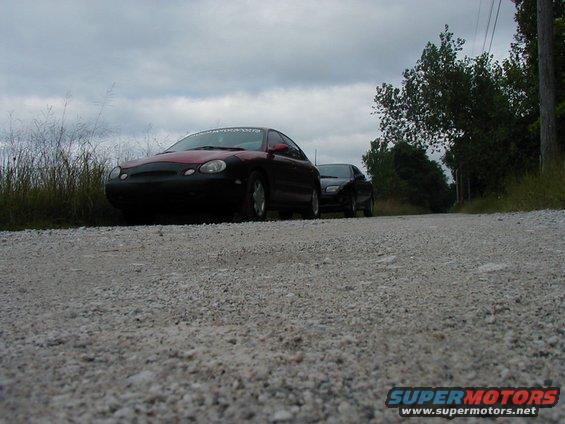 1997 Ford Taurus and another sedan parked on a gravel road