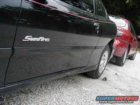 Black Pontiac Sunfire parked next to a red car. "Sunfire" badge visible on the black car's door