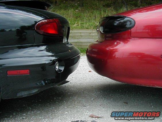 Rear bumper and taillight of a black car next to a red car