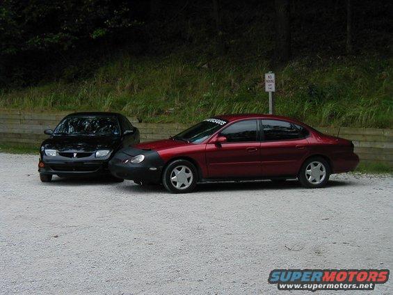 Red sedan with car bra parked next to a black sedan